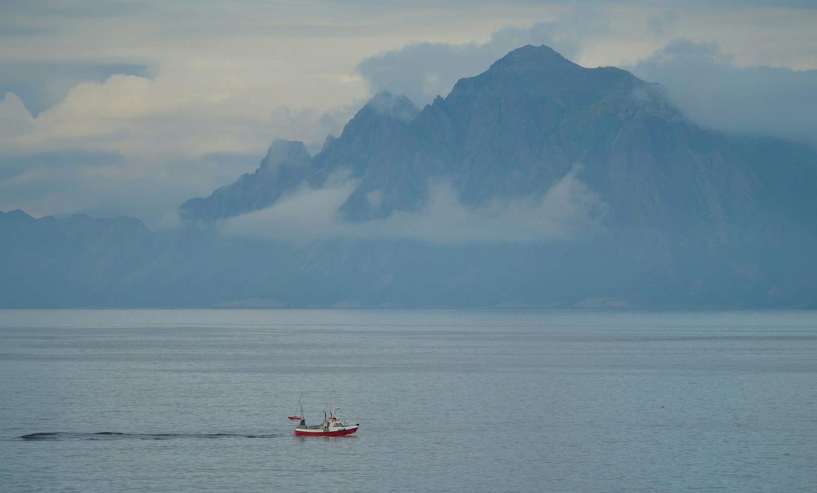 Boat on fjord with cloudy sky